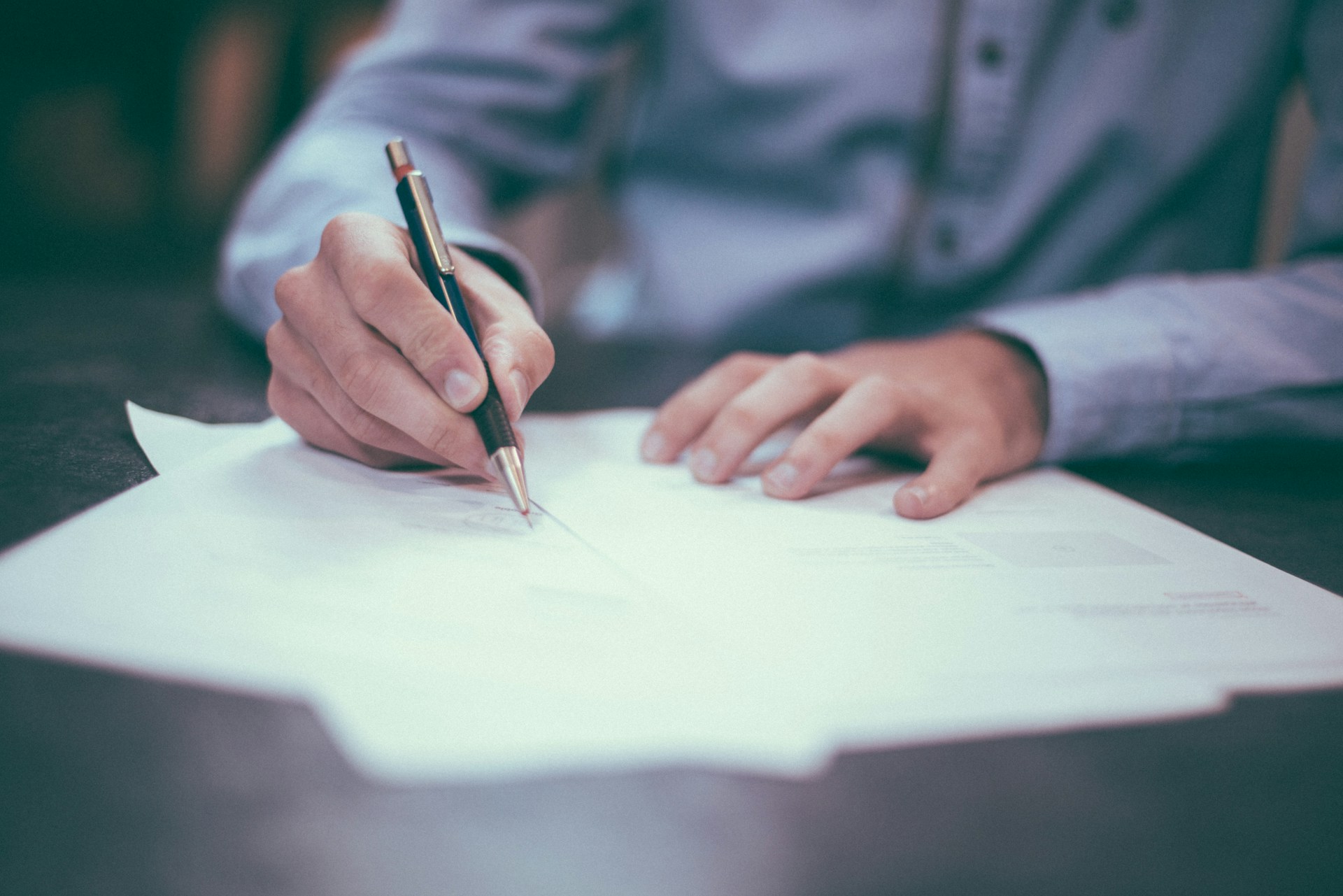 A person signing paperwork at a desk, representing the closing process when buying or selling a home