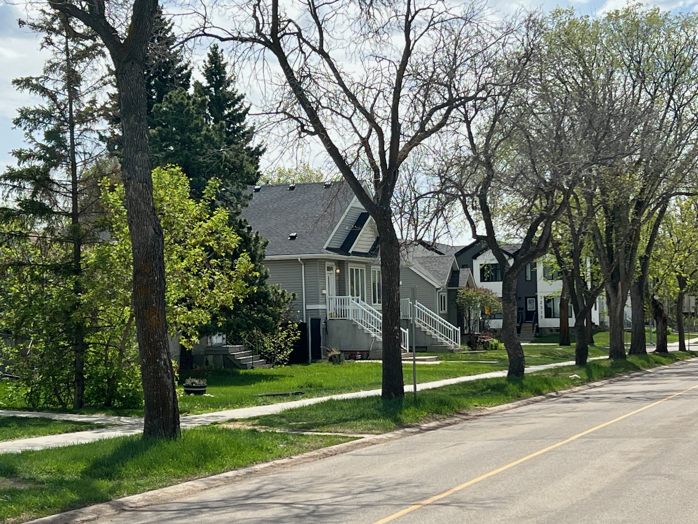Residential street of post-war bungalows with mature trees and front porches in Sherbrooke, Edmonton