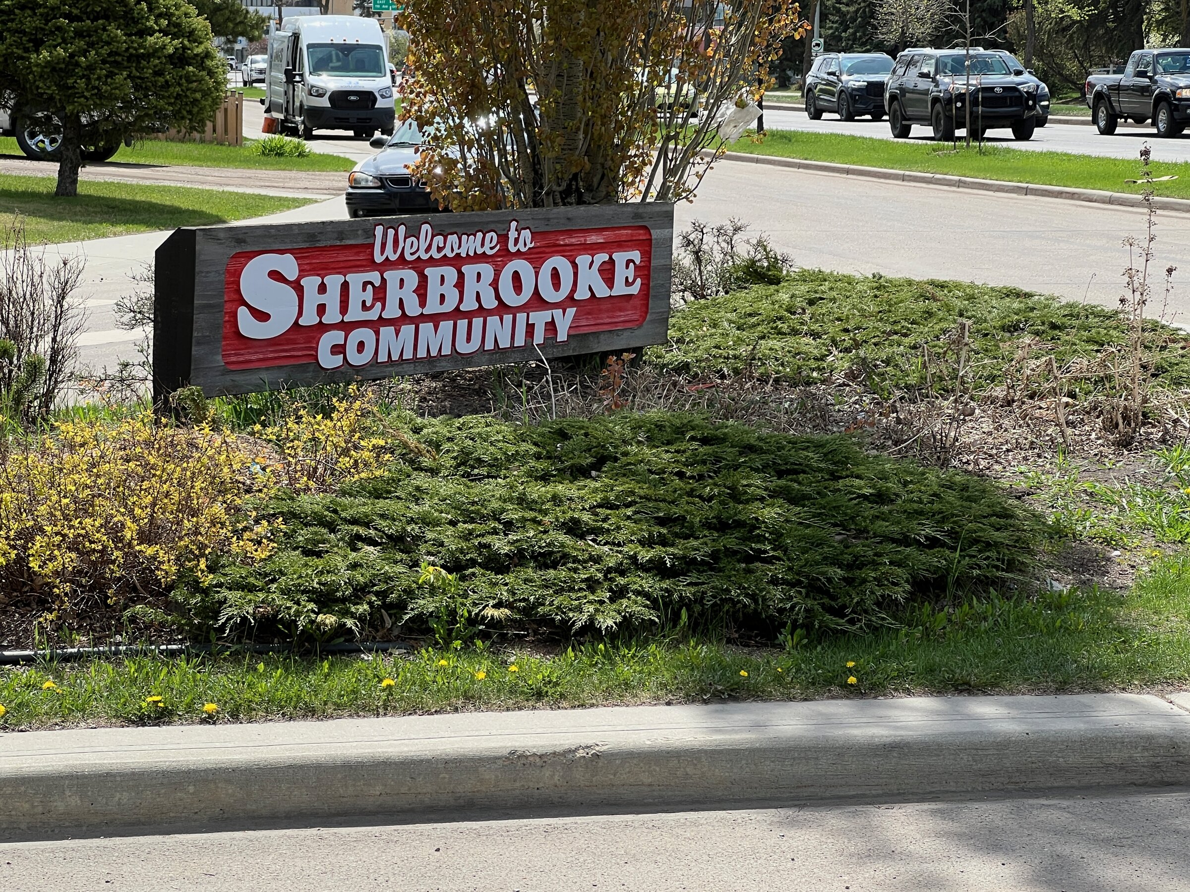 Welcome to Sherbrooke community entrance sign with landscaping and a residential street behind it, in northwest Edmonton