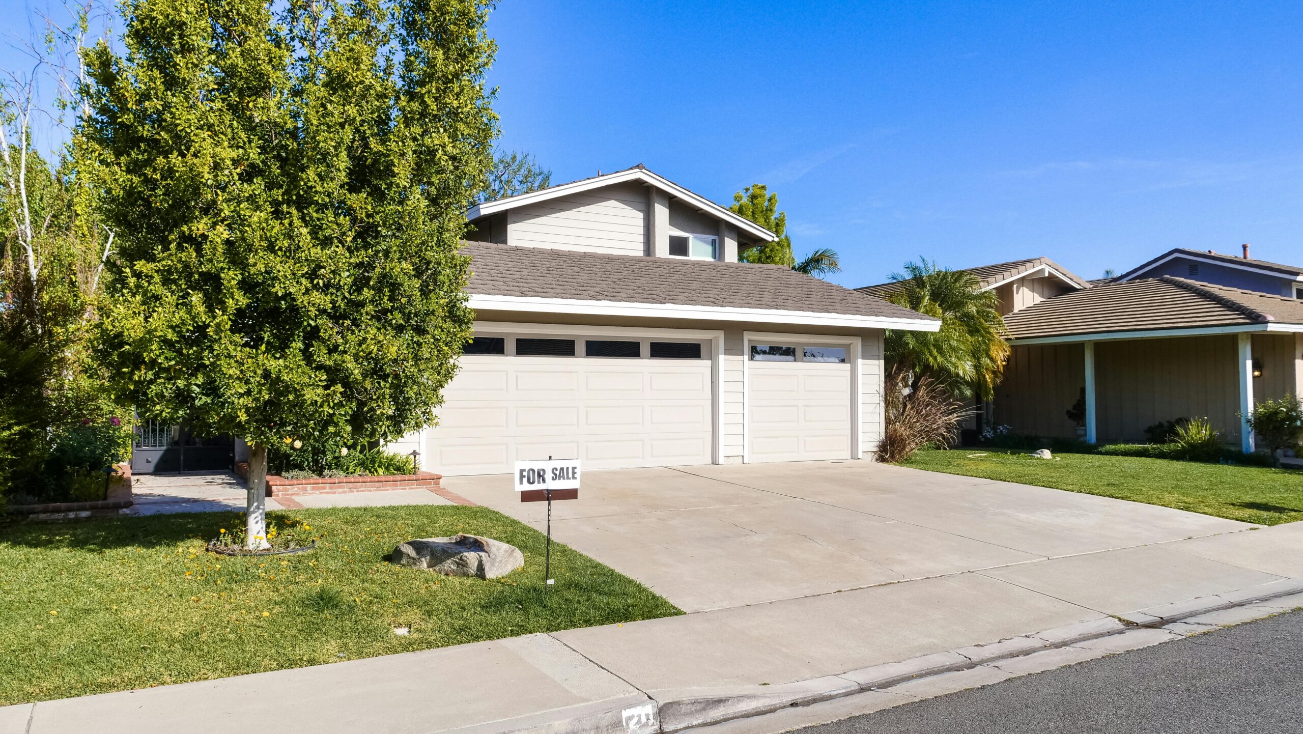 A two-storey suburban home with a three-car garage and a for sale sign on the front lawn, illustrative of the kind of housing found in Keswick, Edmonton